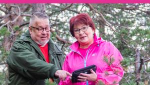 En man och en kvinna i skogen. De tittar tillsammans på en pekplattas skärm.