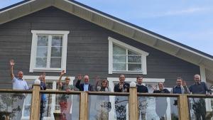 Människor som vinkar från en balkong i en byggnad av trä.