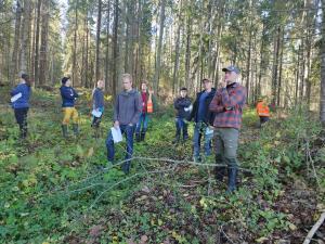 Skogsproffs står i skogen och lär sig känna igen flygekorrmiljöer.