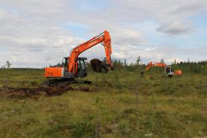 två grävmaskiner i ett träsk