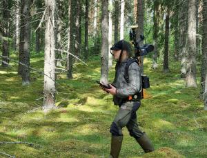 Man går i terrängen med en laserskannare