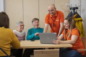 Skogscentralens kundrådgivare visar saker på en dator för några kunder på kontoret.