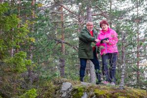 Mies ja nainen ovat metsässä kalliolla ja tutkivat tabletilta tietoja. 