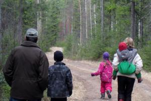 Kaksi aikuista ja lapset kävelevät pitkin metsätietä. 