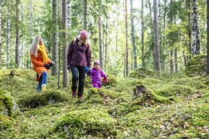 Två kvinnor och ett barn går i skogen på hösten.
