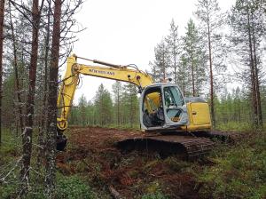 Kaivinkone tukkii ojaa suolla. 