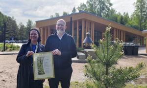 Porin kaupungin Yyterin vierailukeskuksen edustajat pitelevät Pro metsä -palkintodiplomia, vieressä palkintopuuntaimi.