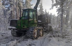 En skogsmaskin på ett körstråk i skogen på vintern.