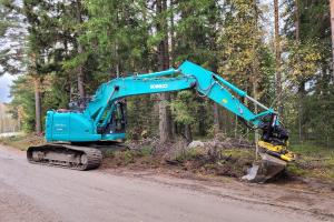 En grävmaskin iståndsätter en skogsbilväg.