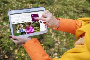 En person håller i en surfplatta och pekar på skärmen mot inloggningspunkten för Metsäkeskus webbplats Metsään.fi-tjänsten.