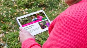 En människa tittar Skogcentralens webbsidor i skogen. 