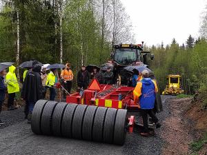Ihmisjoukko katselee suurta tietyökonetta tiellä.