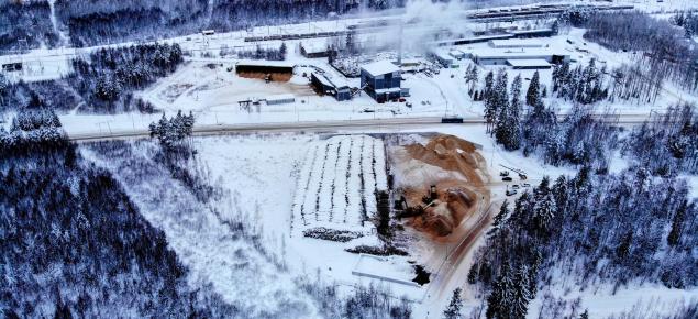 Ilmakuva Imatran Lämmön laitoksesta. Reunoilla näkyy metsää, keskellä lämpölaitoksen rakennus, hakekasoja ja energiapinoja.