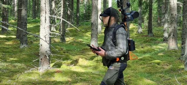 Man går i terrängen med en laserskannare