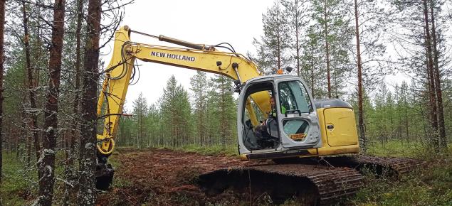 Kaivinkone tukkii ojaa suolla. 