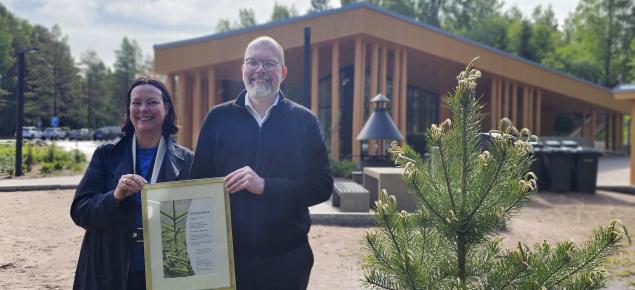 Porin kaupungin Yyterin vierailukeskuksen edustajat pitelevät Pro metsä -palkintodiplomia, vieressä palkintopuuntaimi.
