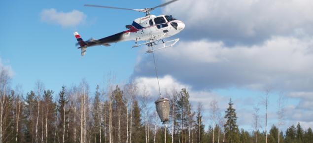 En helikopter sprider aska från luften.