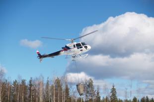 Helikopteri tekemässä metsän terveyslannoitusta.
