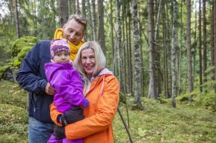 Kaksi aikuista ja lapsi metsässä.