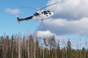 En helikopter sprider aska från luften.