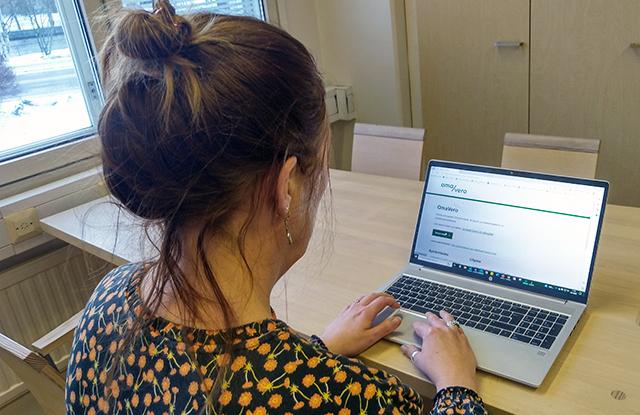 Henkilö istuu tietokoneen ääressä selin kameraan. Tietokoneen näytöllä näkyy OmaVero-palvelu.