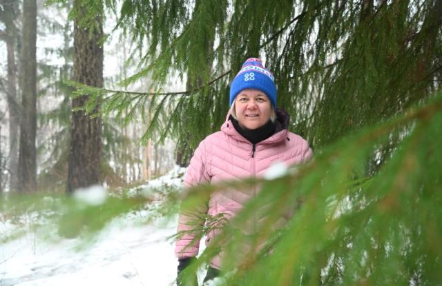 En kvinna i skogen, i skydd av grangrenarna.